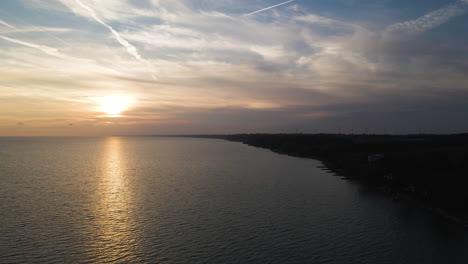 vista panorámica aérea por encima de la silueta oscura de la tierra mientras el sol se pone en el horizonte por encima del lago