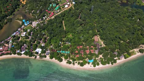 aerial down shot of tropical island small bungalow resorts, drone, bird’s eye view down shot with lush green rain forest and tropical palm trees with white sand beach