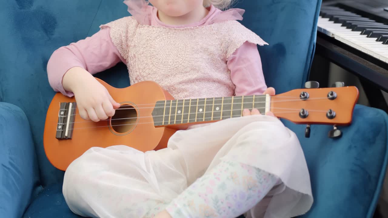 Young and happy girl plays guitar (ukulele), close up