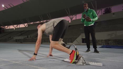 entrenador masculino diverso y atleta masculino discapacitado con cuchilla de correr preparándose para comenzar una carrera