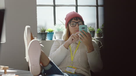 Joven-Mujer-De-Negocios-Que-Utiliza-Un-Teléfono-Inteligente-Para-Navegar-Por-La-Información-Del-Proyecto-En-La-Pantalla-Del-Teléfono-Móvil-Leyendo-Estadísticas-De-Estudios-De-Investigación-Intercambiando-Ideas-Relajando-Los-Pies-En-La-Mesa-En-Una-Oficina-Moderna