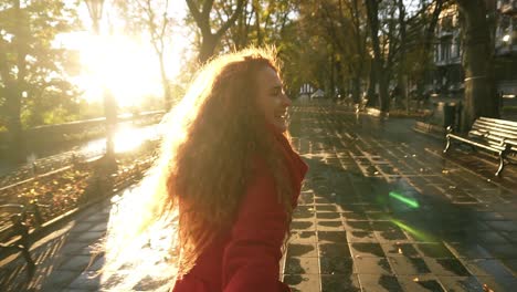 Schöne-Junge-Frau-Mit-Rotem-Kopf,-Die-Freudig-In-Einem-Farbenfrohen-Herbstpark-Durch-Eine-Gasse-Läuft-Und-Herbstlaub-Genießt,-Dreht-Sich-Um-Und-Lächelt-Freudig-In-Die-Kamera