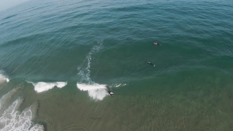 visión general de fpv en cámara lenta y alta aérea de un bodyboarder experto realizando una maniobra de giro de ars air roll en la cara de onda abierta en un día soleado y claro con arena tirando de debajo del agua