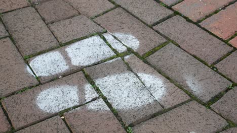 white painted social distance corona virus information on town brickwork flooring