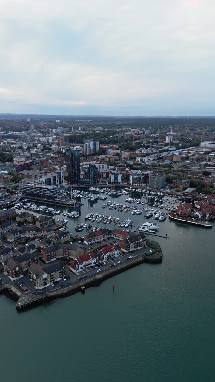 Aerial drone footage of Ocean Village marina in Southampton, showcasing boats, docks, buildings, and waterfront real estate under soft daylight at sunset shot during autumn
