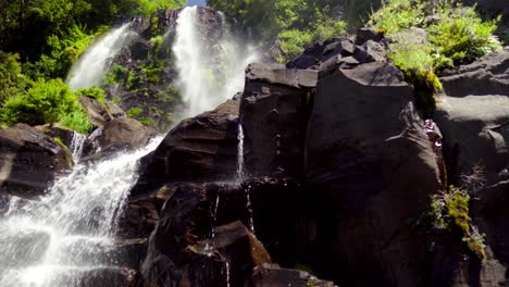 Misty-Niña-Encantada-waterfall-streaming-down-rocks-surrounded-by-green-dense-rainforest-at-daytime,-in-Liquiñe,-Chile