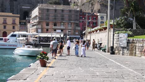 people walking by yachts in sorrento, italy