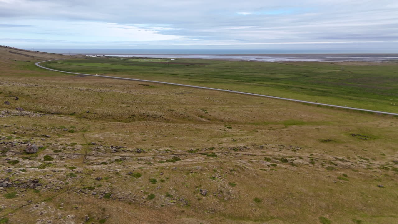 Aerial view of steep mountain cliffs in Sveitarfélagið Hornafjörður, showing layered rock formations, glacial valley textures, and sweeping rugged terrain under an overcast sky