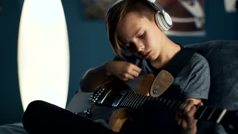 boy in headphones learning song with guitar