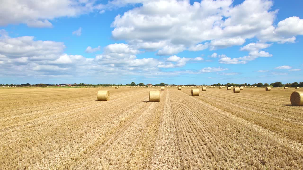 Aerial footage captures the serenity of wind turbines in a Lincolnshire farmer's freshly harvested field, with golden hay bales adding a touch of charm to the scene