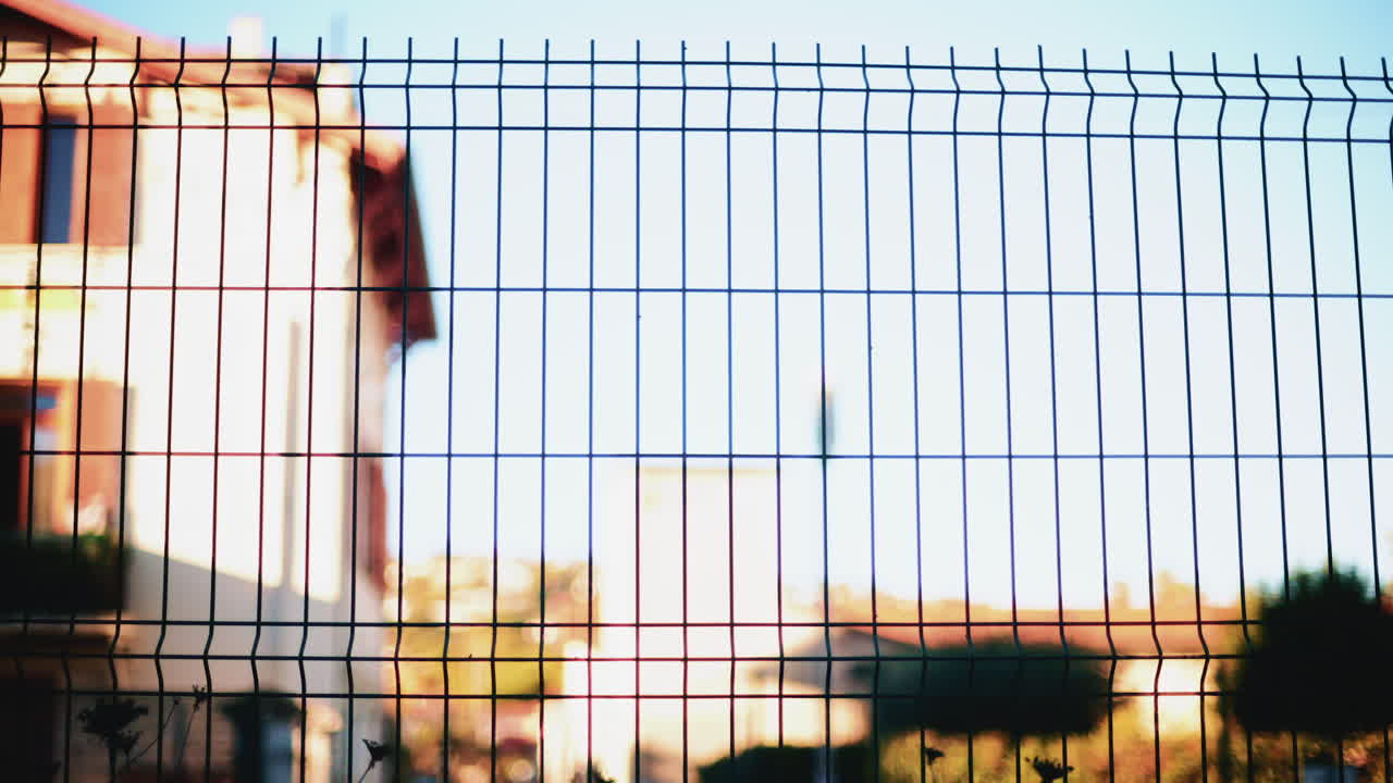 Blurred train passing behind a metal fence, creating an abstract transportation scene with strong graphic lines