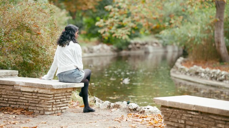 Woman sitting on a bench by a lake in autumn