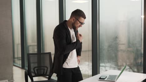 hombre enojado con ropa de negocios en la oficina tratando de reparar una computadora portátil rota y no funciona