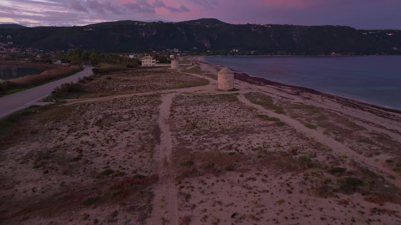 I mulini a vento fiancheggiano la pacifica costa ionica all'alba, Lefkada, Grecia