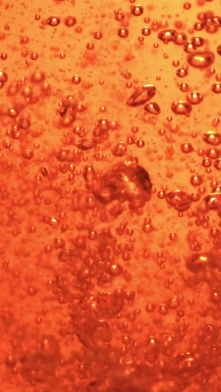 Primo piano di bollicine effervescenti arancioni che salgono in un liquido