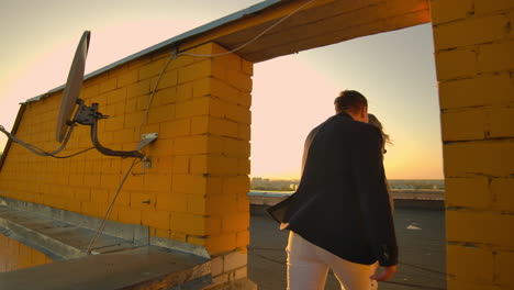 A-man-with-a-woman-running-on-the-roof-holding-hands.-Slow-motion-lovers-on-the-roof.