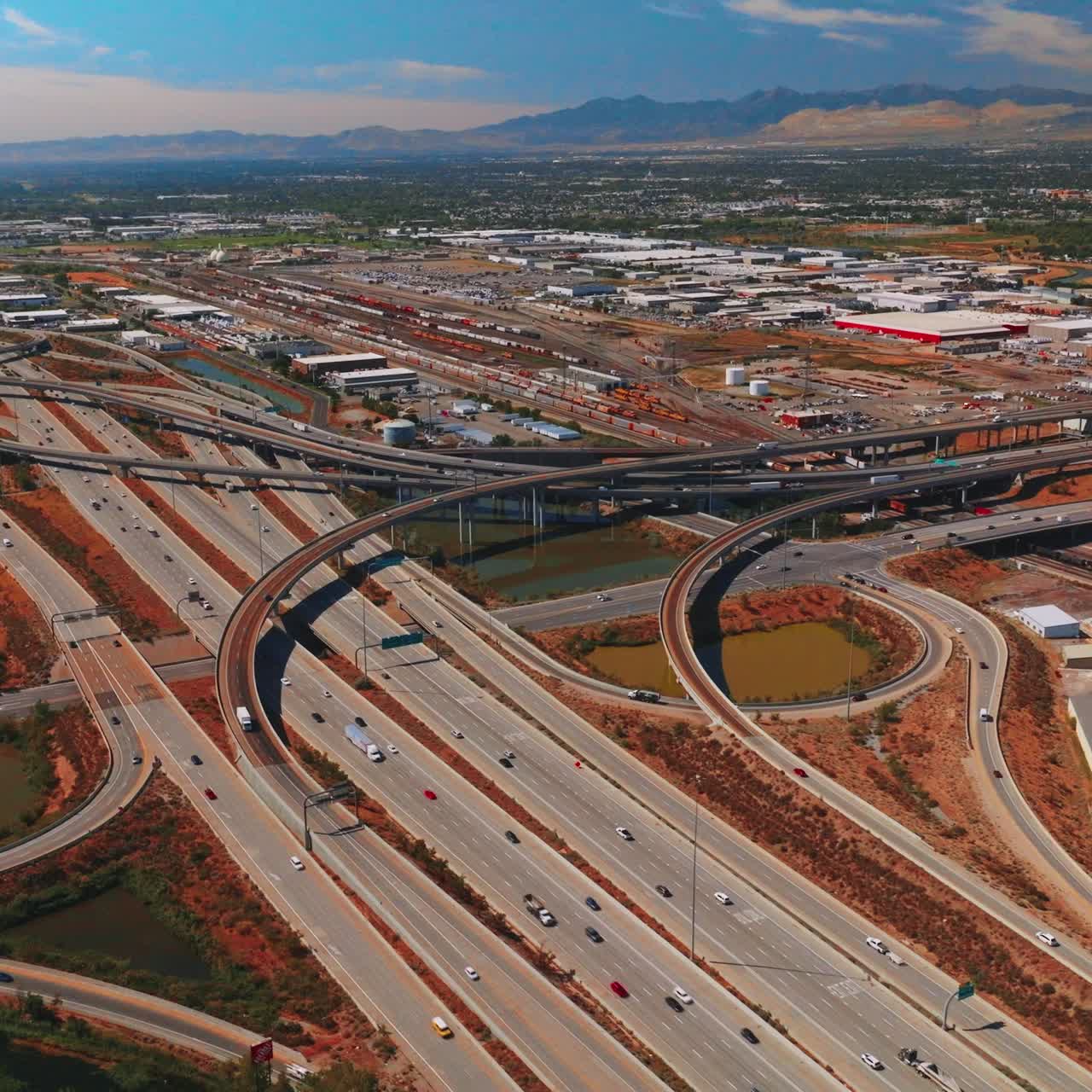 Plexus of roads and skyways at outskirts of Salt Lake City on sunny day. Mountains at backdrop. Aerial perspective