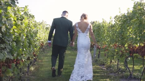 Bride-and-groom-laugh-smile-and-hold-hands-while-walking-into-the-sunset