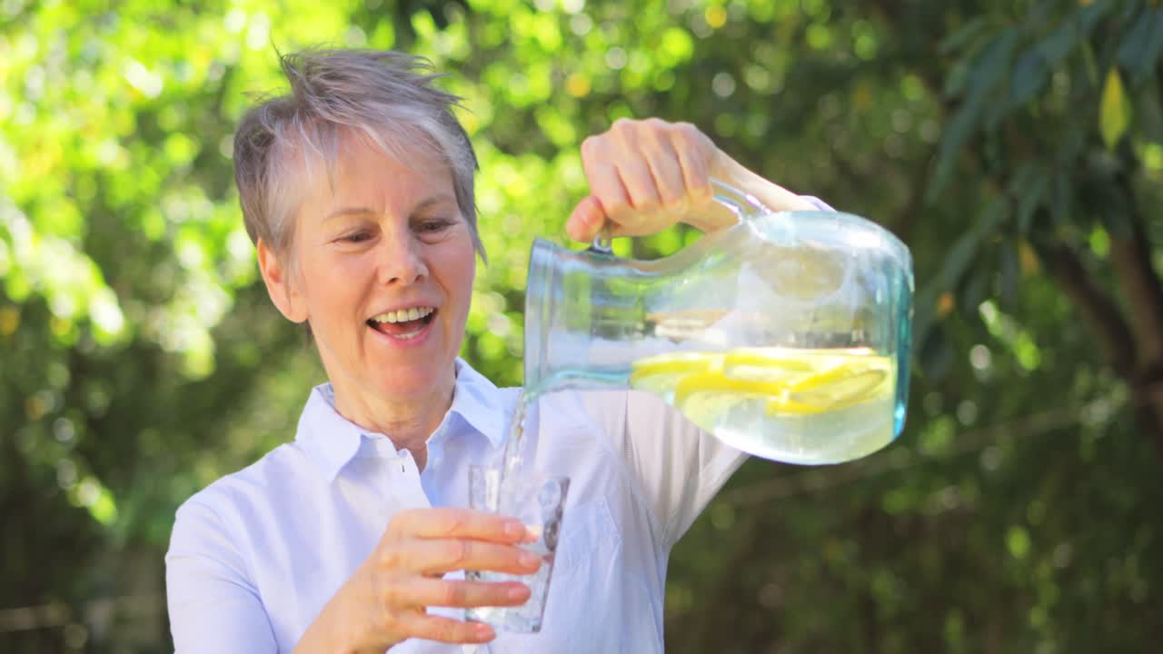 Senior woman pouring lemonade from a jug