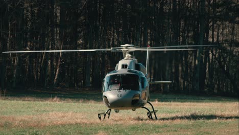 a helicopter idles in a field as its rotors spin