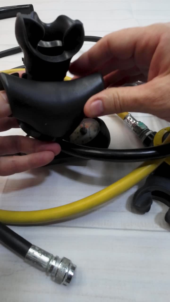 Woman hands checking mouthpiece and hose connections of scuba diving regulator
