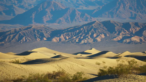 Ondulantes-Dunas-De-Arena-De-Mezquite-Con-Montañas-En-Un-Fondo-Distante