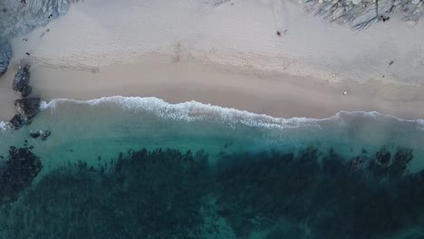 Aerial-ascending-birdseye-view-from-the-picturesque-coastline-in-los-cabos-directly-at-monument-beach-with-fine-sand,-calm-waves-and-scattered-rock-formations-near-the-cape-thompson-hotel-in-mexico