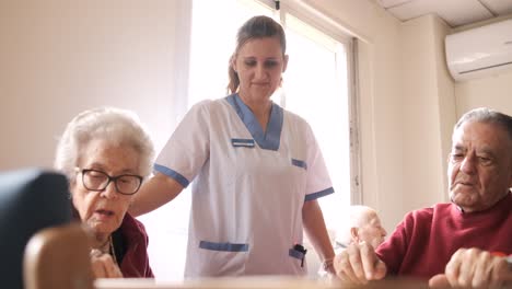 senior people playing domino game while nurse helping