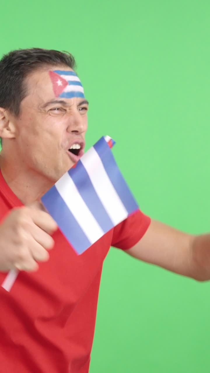 Man cheering for Cuba waving a national flag looking away