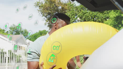 man retrieving yellow pool tube from car trunk, showing floating environmental icons