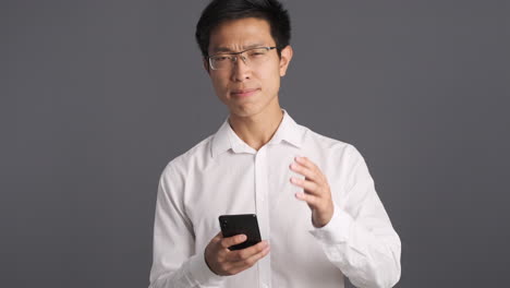 Asian-man-using-smartphone-getting-annoyed.