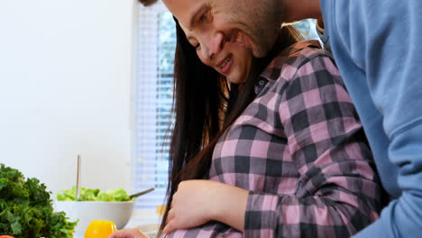 Man-touching-pregnant-womans-belly-while-cutting-vegetables-4k