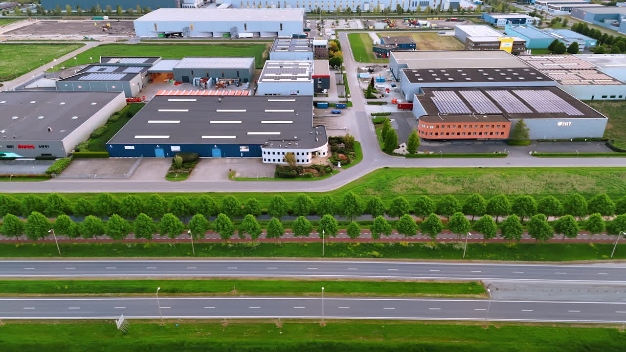 Flight along the roads outlined by the lawns and rows of trees. Large low rise premises on the other side of the highways. The Netherlands.