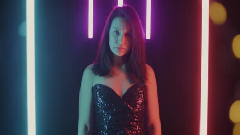 woman in a sparkly sequin dress under vibrant neon lights