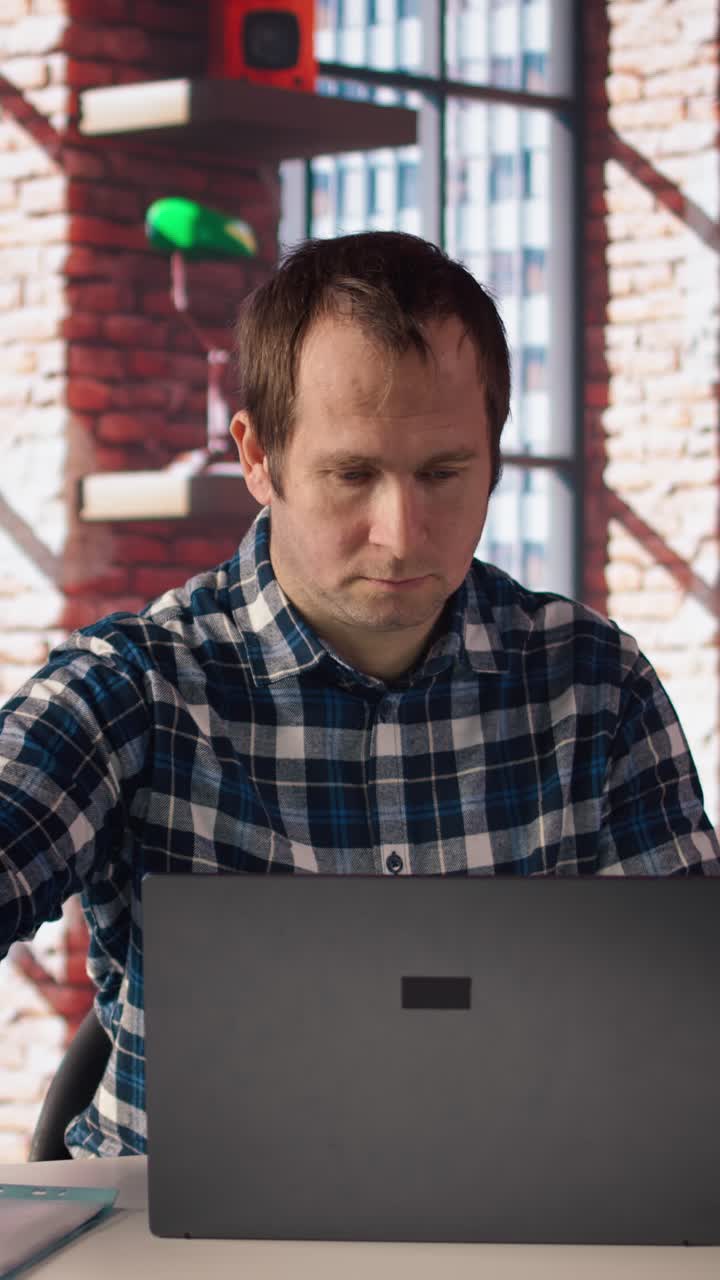 Vertical video Employee completing spreadsheets on laptop and listening music