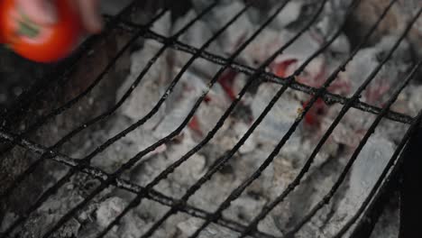 el cocinero pone los tomates en la parrilla de carbón para preparar una cocina mediterránea saludable