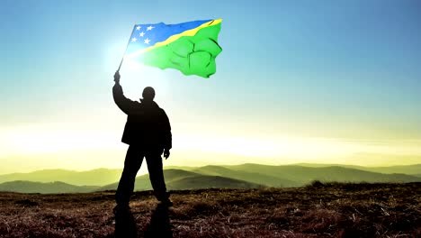 successful silhouette man winner waving solomon islands flag on top of the mountain peak, cinemagraph loop background