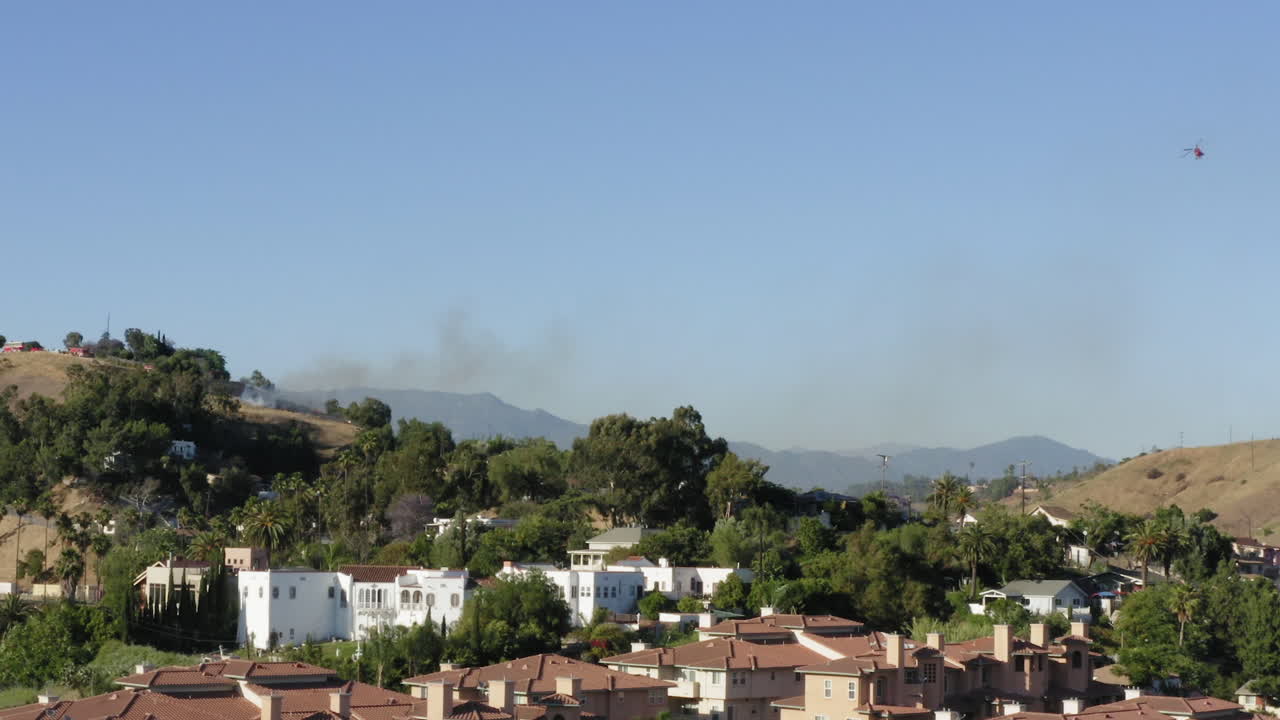 Luchtfoto van een helikopter die een bosbrand blust in Lincoln Heights, een voorstad van Los Angeles
