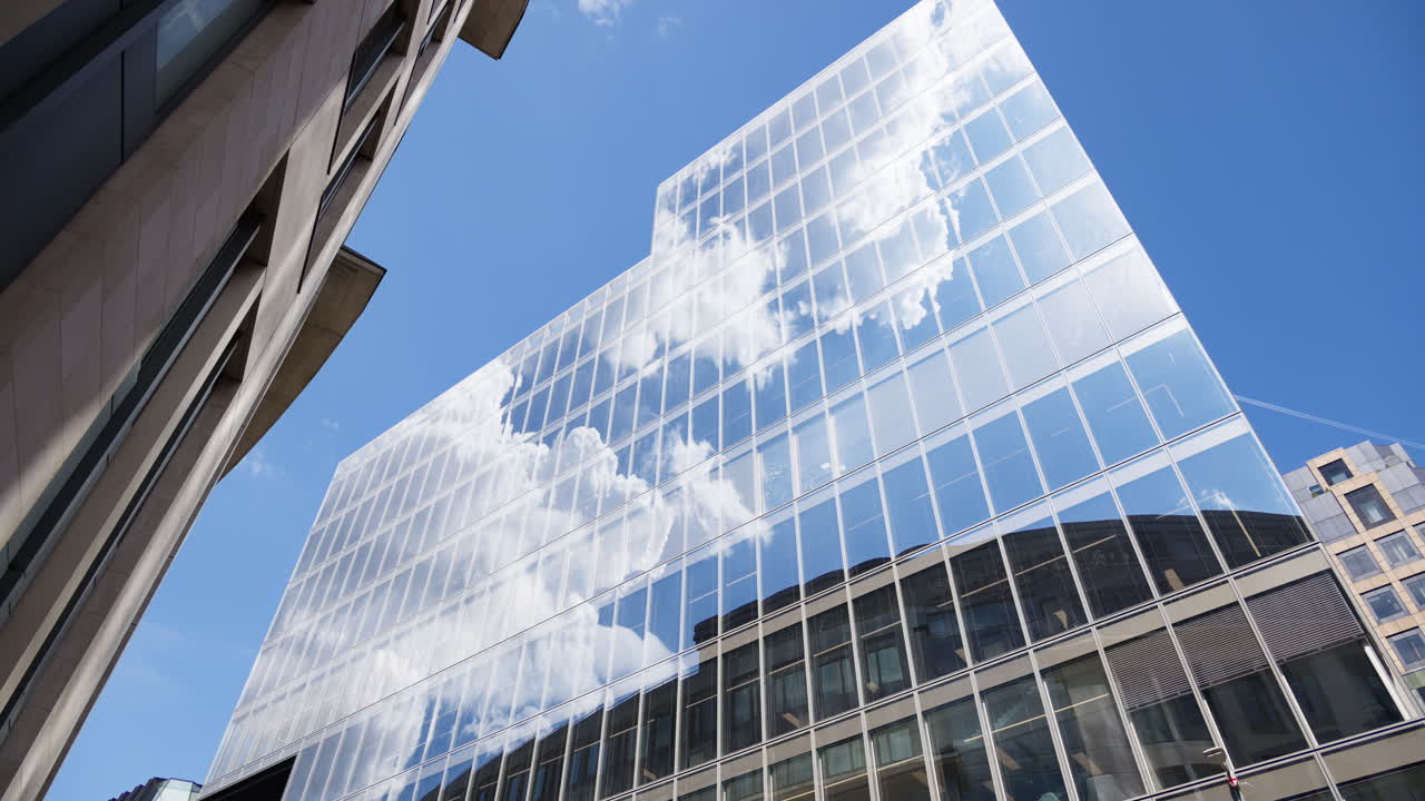 Modern glass skyscrapers of London's financial district reflecting the blue sky next to historic architecture