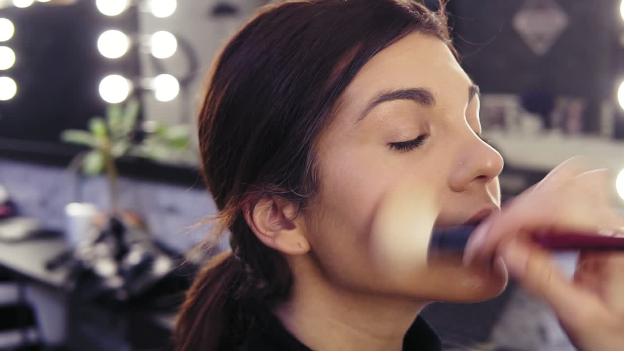 proceso de creación impecable sin maquillaje aspecto. aplicando polvo con un pincel especial. joven atractiva chica morena con hermosos ojos de avellana