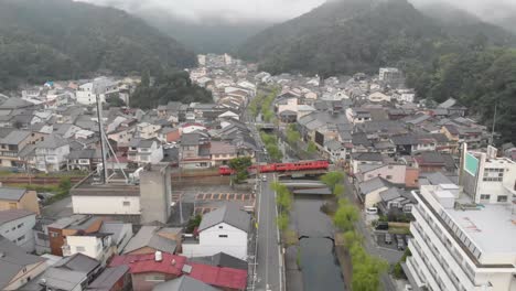 early morning aerial shot of kinosaki onsen, famous small hot spring town in hyogo prefecture, jr train passing through town and crossing river