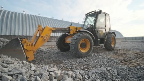 tractor moves rubble to truck. excavator-loader rakes rubble from pile at construction site and loads dump truck. clearing site