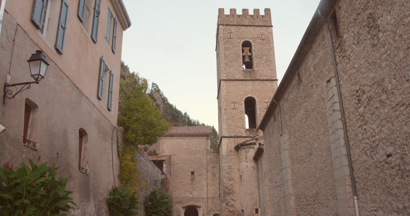 Ancient stone church with bell tower in Entrevaux, one of France's most beautiful villages. Medieval Provençal architecture with narrow streets and historic buildings in French Alpes.