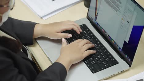 las manos de la mujer de negocios escribiendo en el teclado de la computadora portátil para buscar información, informe de investigación de marketing en el escritorio de la oficina