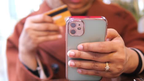 woman using her phone and credit card to shop online