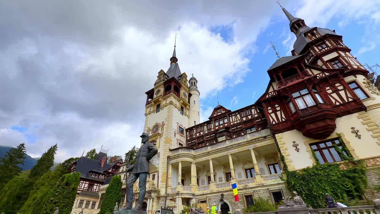 King Carol I statue at the front façade of the beautiful Peles Castle, Prahova County, Romania. Low angle view at the landmark against dramatic cloudscape in the sky