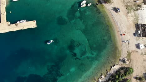 Sea-bay-with-turquoise-calm-water-of-Mediterranean-and-anchored-fishing-boats-near-pier