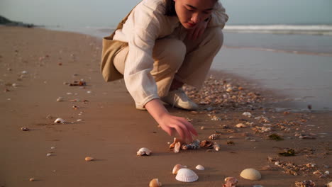 person walking and collecting seashells on a sandy beach