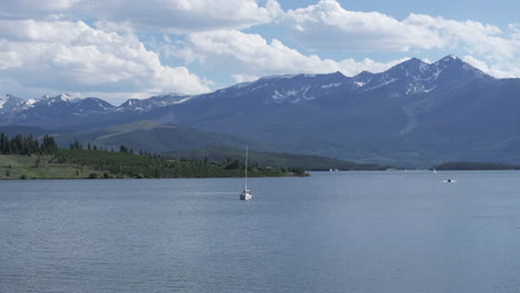 lake dillon, colorado usa, drone shot of sailboat in water reservoir with snow mountain in background