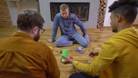 afro-american man rolling dice, poker chips on the floor, friends having fun